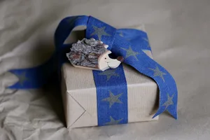 Gift box wrapped by kraft brown paper with blue jeans ribbon and handmade wooden hedgehog small toy. © Elena Popova/Getty Gift box wrapped by kraft brown paper with blue jeans ribbon and handmade wooden hedgehog small toy. © Elena Popova/Getty