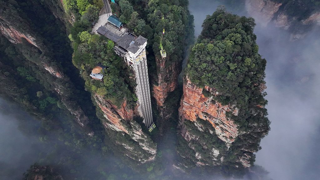 In an aerial view, mist and clouds shroud 326-meter-tall Bailong Elevator at Zhangjiajie National Forest Park 