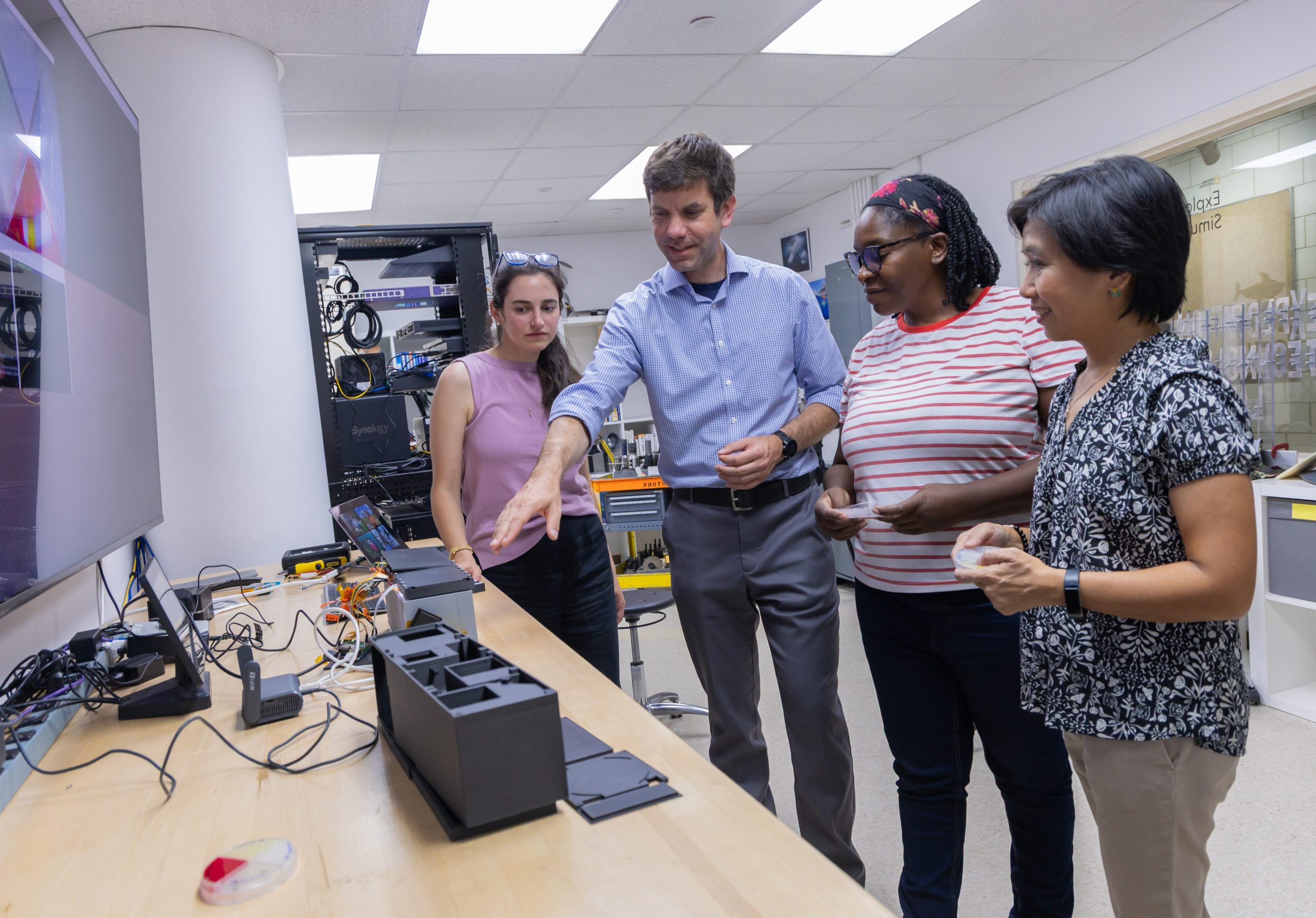 Andrew Klesh,
PhD. (center, wearing blue shirt), Associate Director & Chief Systems Engineer, Brinson Exploration
Hub, with National Geographic Explorers Gabrielle Corradino (far left), Moola Mutondo (second
from right) and Suchana "Apple" Chanavich (far right) discussing the “Nanolab.”